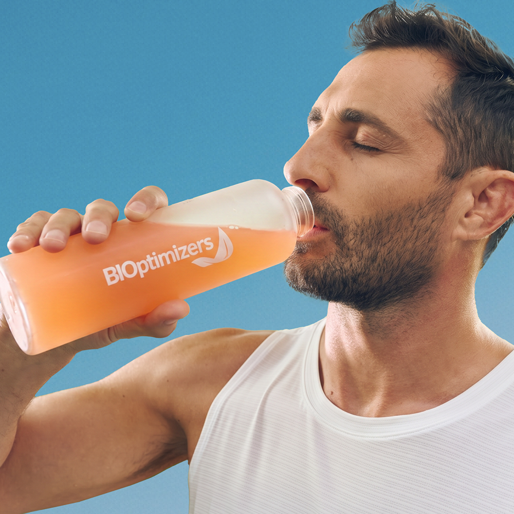 Man drinking a BiOptimizers hydration bottle outdoors
