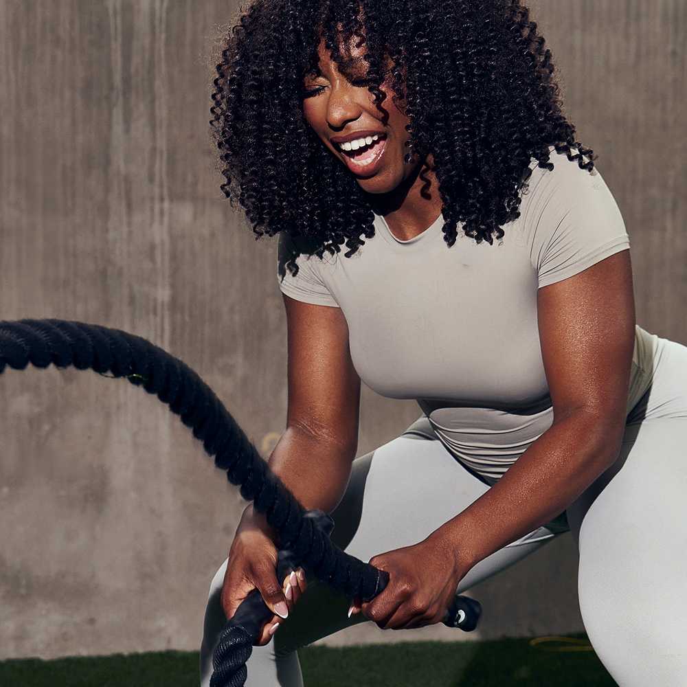 Woman training with battle ropes on a turf field